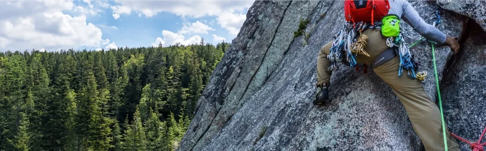 man trad climbing with lots of gear